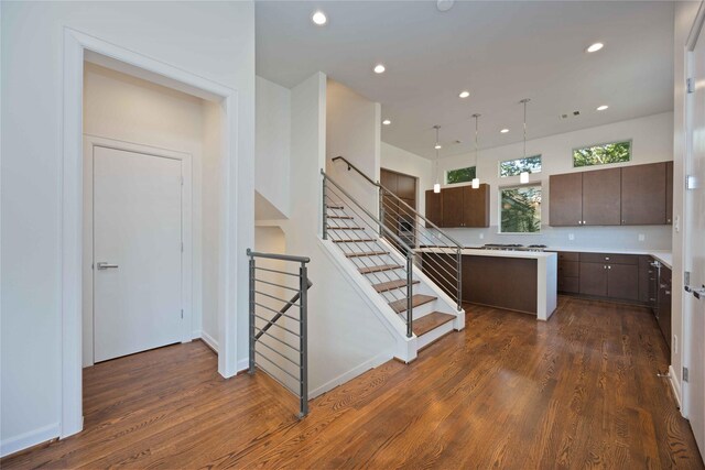 kitchen featuring dark brown cabinets, a kitchen island, dark wood-type flooring, and decorative light fixtures