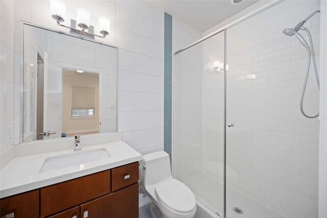 bathroom with walk in shower, vanity, tile walls, and toilet