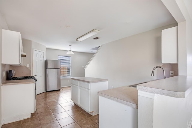 kitchen with white cabinetry, sink, a kitchen island, stainless steel fridge, and light tile patterned floors