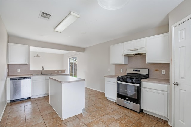 kitchen featuring appliances with stainless steel finishes, sink, pendant lighting, white cabinetry, and a kitchen island