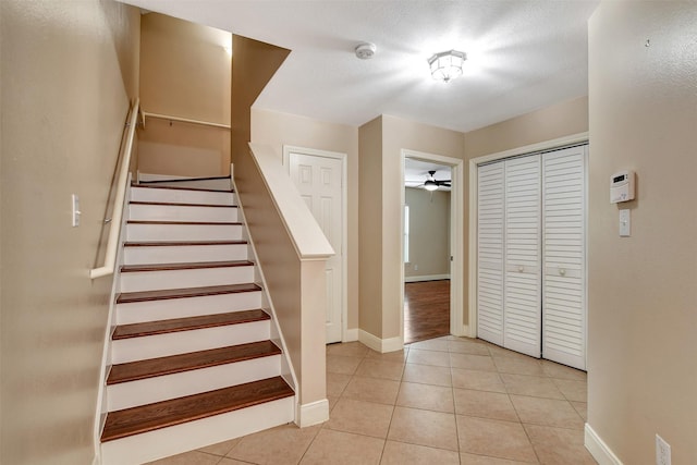 stairway featuring ceiling fan, tile patterned flooring, and a textured ceiling