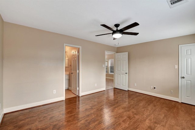 unfurnished bedroom featuring ensuite bath, ceiling fan, and dark wood-type flooring