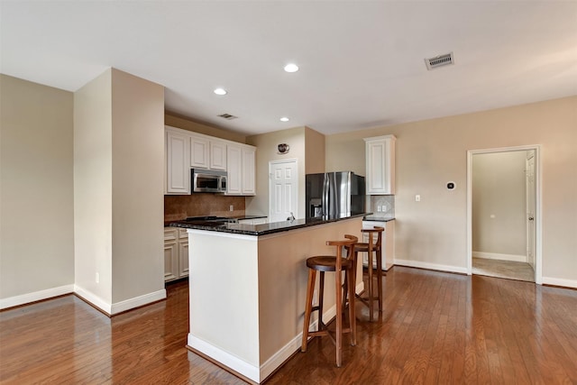 kitchen featuring white cabinets, dark hardwood / wood-style floors, decorative backsplash, a kitchen island, and stainless steel appliances