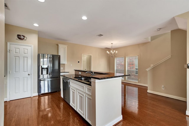 kitchen featuring appliances with stainless steel finishes, dark wood-type flooring, sink, a center island with sink, and white cabinets