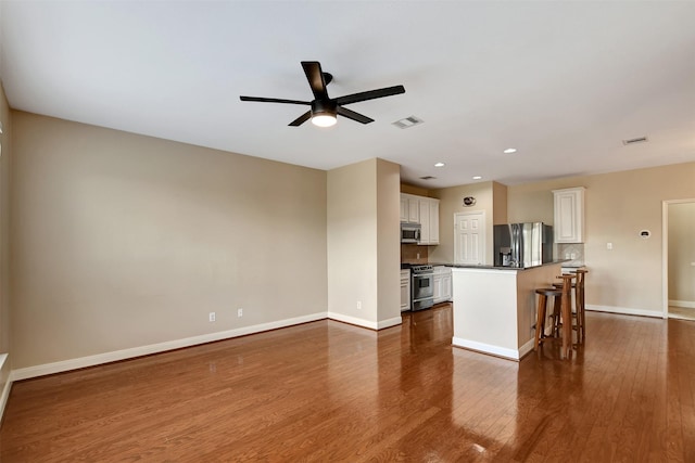 unfurnished living room featuring ceiling fan and dark wood-type flooring