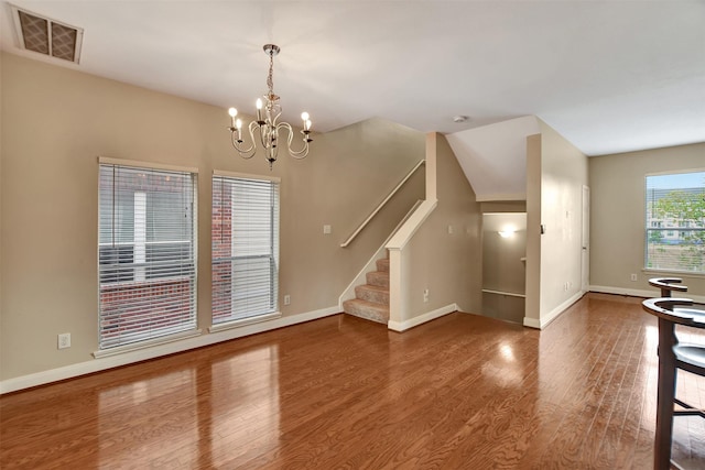 unfurnished living room with hardwood / wood-style floors and an inviting chandelier