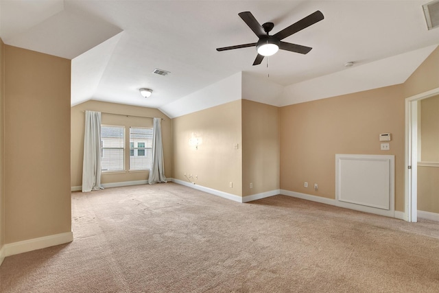 carpeted spare room featuring vaulted ceiling and ceiling fan