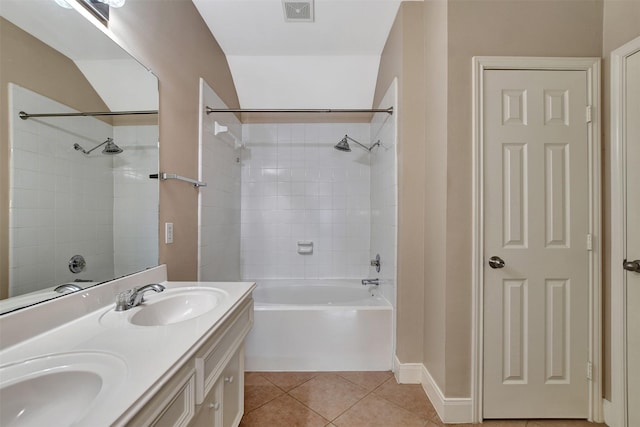 bathroom featuring tile patterned floors, vanity, tiled shower / bath combo, and vaulted ceiling