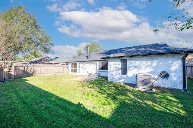 rear view of property with central AC unit and a yard