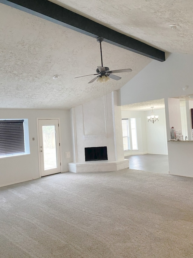 unfurnished living room featuring plenty of natural light, a textured ceiling, lofted ceiling with beams, and a fireplace