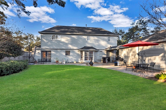 rear view of house with a patio area, a lawn, and fence