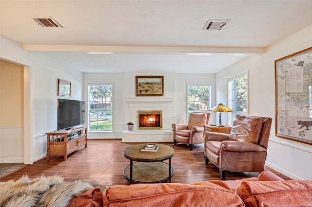 living room with hardwood / wood-style flooring, a brick fireplace, and beamed ceiling