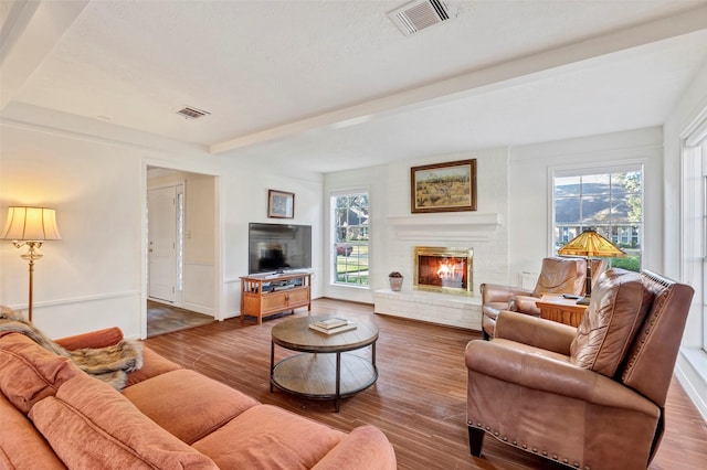 living room with beamed ceiling, wood-type flooring, and a fireplace