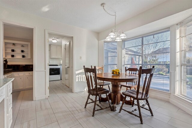 dining room featuring an inviting chandelier, washer / clothes dryer, and a textured ceiling