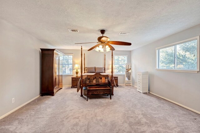 bedroom with light carpet, a textured ceiling, and ceiling fan