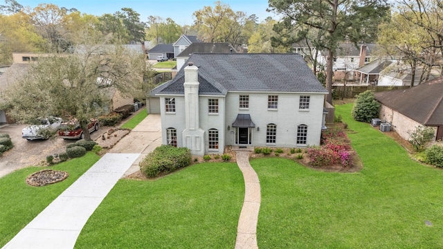 view of front of property with central AC, a chimney, concrete driveway, a front lawn, and brick siding