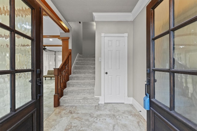 foyer featuring crown molding, stairway, and baseboards