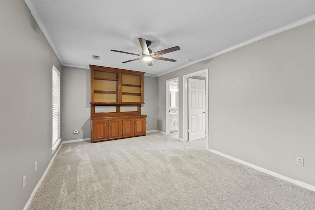 carpeted empty room featuring crown molding, ceiling fan, and a textured ceiling