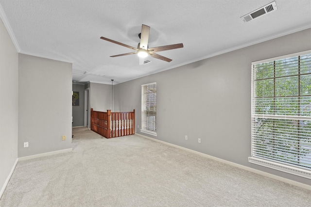 unfurnished room featuring visible vents, a textured ceiling, carpet floors, crown molding, and baseboards