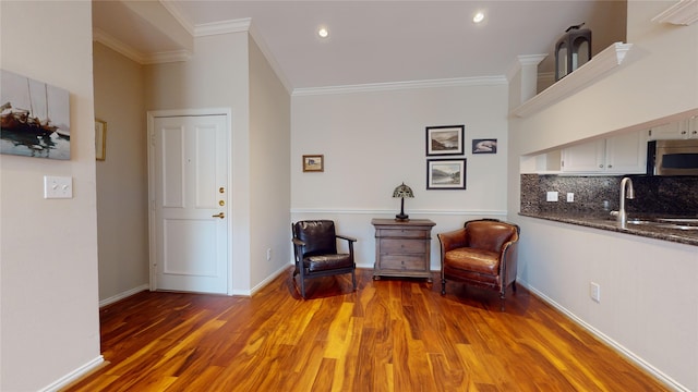 sitting room with sink, wood-type flooring, and ornamental molding