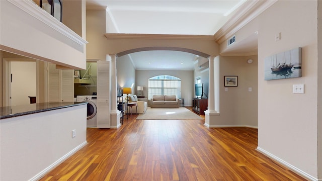 foyer featuring hardwood / wood-style floors, ornamental molding, washer / clothes dryer, and decorative columns