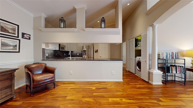 kitchen featuring kitchen peninsula, appliances with stainless steel finishes, light hardwood / wood-style floors, and washer / dryer