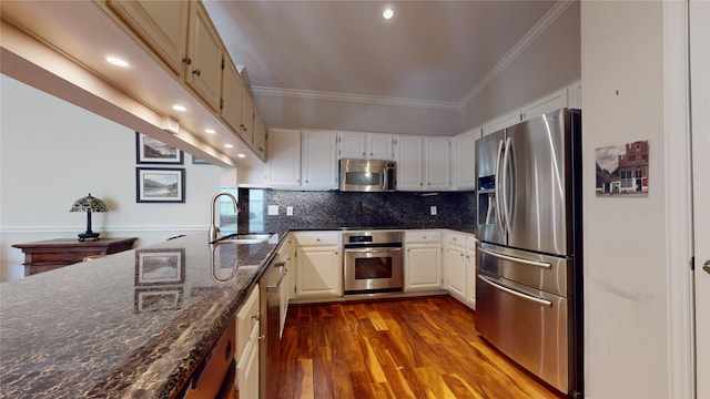 kitchen featuring hardwood / wood-style floors, sink, vaulted ceiling, dark stone countertops, and stainless steel appliances