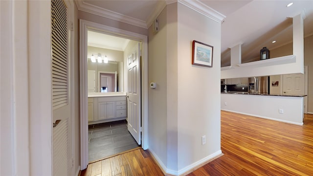 corridor featuring light wood-type flooring, vaulted ceiling, and ornamental molding