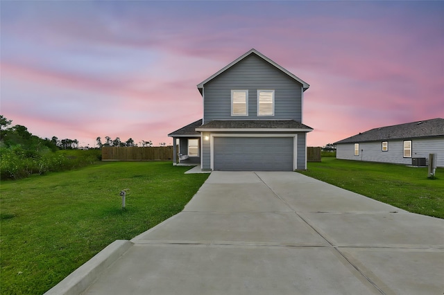 view of front of property featuring a garage, a yard, and central AC