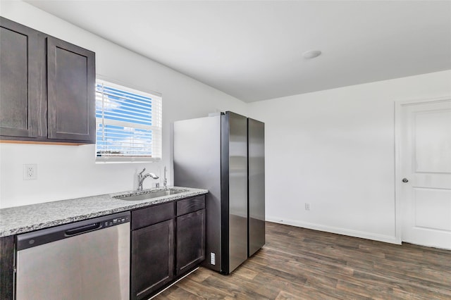 kitchen with light stone counters, appliances with stainless steel finishes, sink, and dark brown cabinets