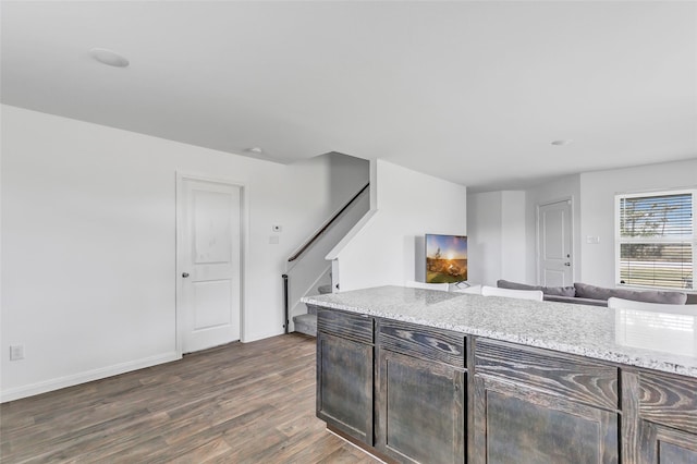 kitchen with dark hardwood / wood-style flooring, light stone countertops, and dark brown cabinets