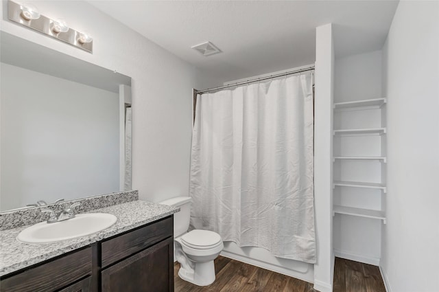 full bathroom with hardwood / wood-style flooring, vanity, shower / tub combo, toilet, and a textured ceiling