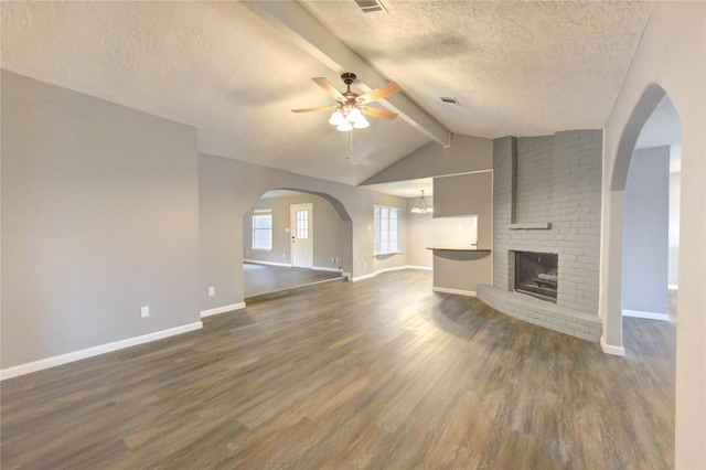 unfurnished living room featuring ceiling fan, a brick fireplace, vaulted ceiling with beams, a textured ceiling, and dark hardwood / wood-style flooring