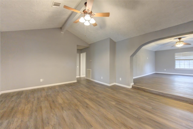 unfurnished living room with a textured ceiling, vaulted ceiling with beams, dark hardwood / wood-style floors, and ceiling fan