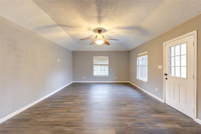 unfurnished room featuring ceiling fan, vaulted ceiling, dark hardwood / wood-style flooring, and a textured ceiling