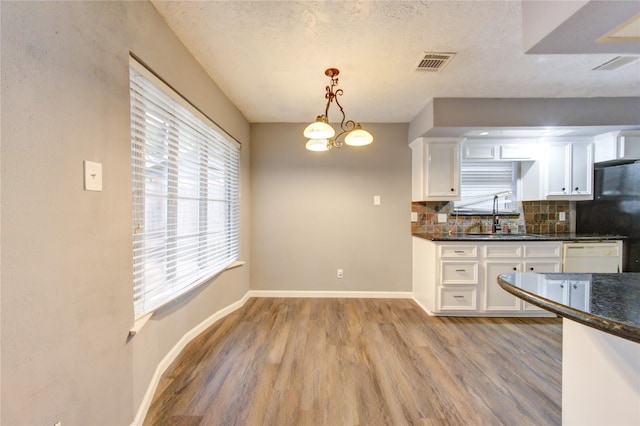 kitchen with white cabinets, backsplash, sink, and pendant lighting