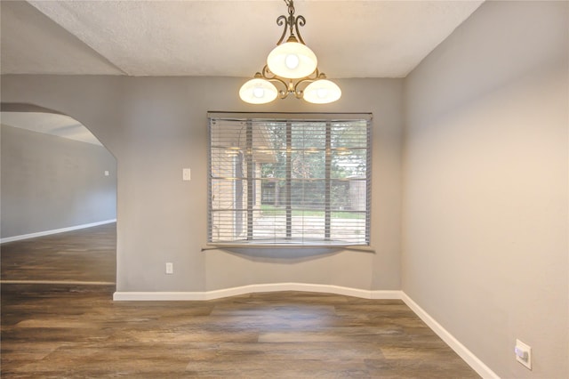 unfurnished dining area featuring a textured ceiling, dark wood-type flooring, and a chandelier