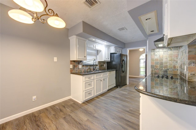 kitchen featuring white cabinetry, decorative light fixtures, dark stone countertops, black appliances, and sink