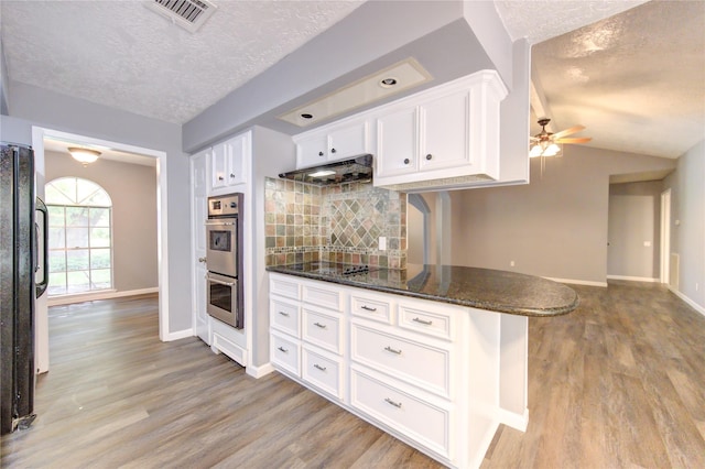 kitchen featuring a textured ceiling, kitchen peninsula, white cabinetry, and tasteful backsplash