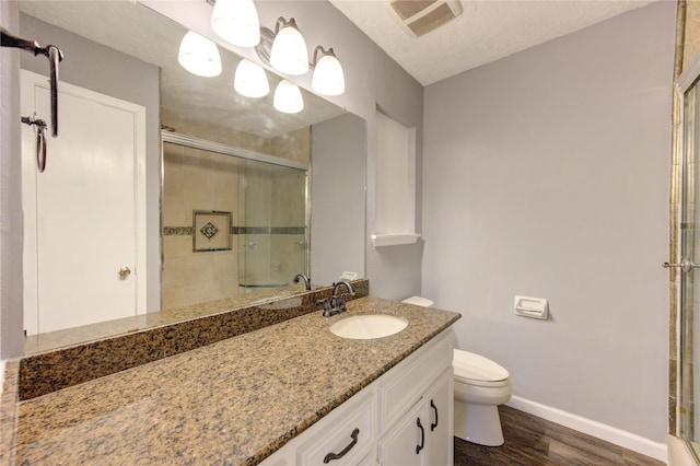 bathroom featuring a textured ceiling, an enclosed shower, vanity, toilet, and hardwood / wood-style flooring