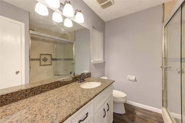 bathroom with toilet, vanity, an enclosed shower, and hardwood / wood-style floors