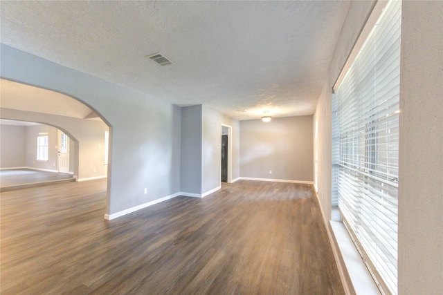 empty room with a textured ceiling and dark hardwood / wood-style flooring