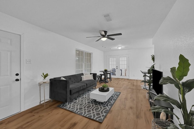 living room featuring ceiling fan, wood-type flooring, and french doors