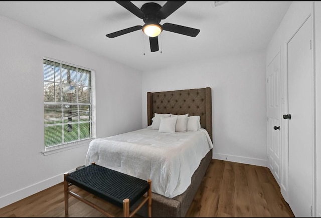 bedroom featuring ceiling fan, dark hardwood / wood-style floors, and multiple windows