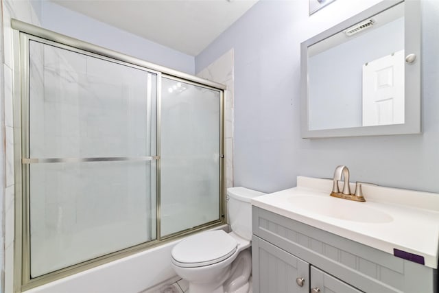 full bathroom featuring vanity, combined bath / shower with glass door, and toilet