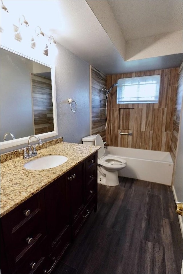 full bathroom with hardwood / wood-style flooring, tiled shower / bath, vanity, and toilet