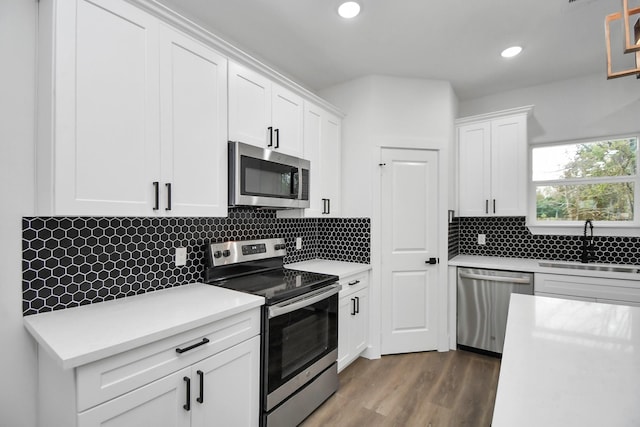 kitchen with dark wood-type flooring, stainless steel appliances, tasteful backsplash, white cabinetry, and sink