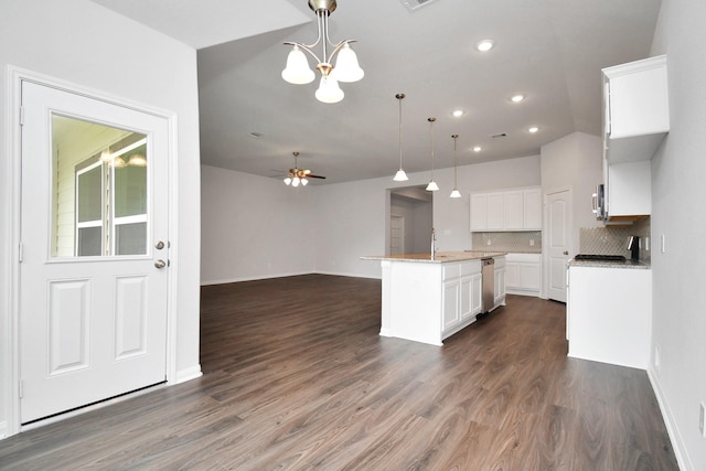 kitchen with pendant lighting, dark wood-type flooring, a center island with sink, ceiling fan with notable chandelier, and white cabinets