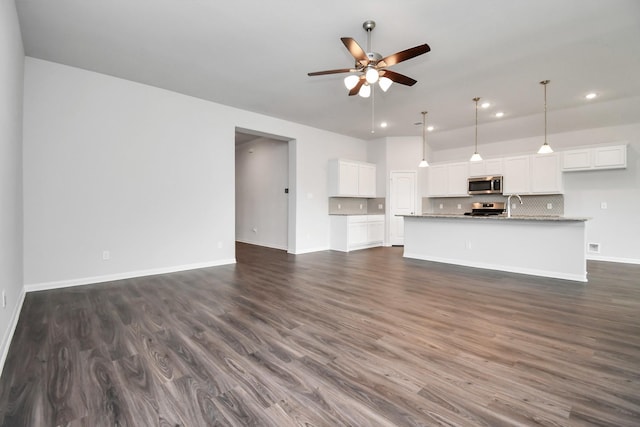 unfurnished living room featuring dark hardwood / wood-style floors, ceiling fan, and sink