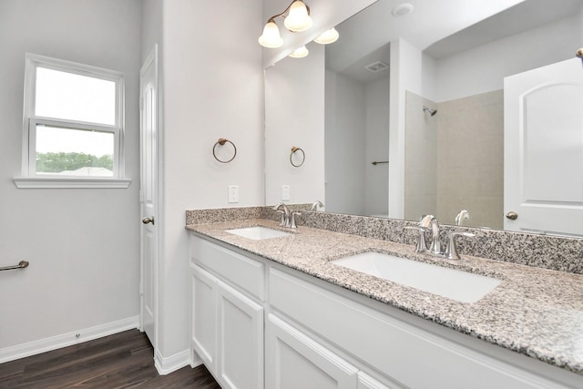 bathroom featuring hardwood / wood-style flooring, vanity, and a tile shower